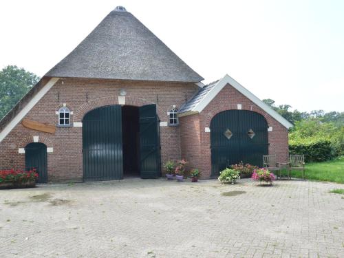een rood bakstenen gebouw met twee poorten en bloemen bij Quaint Farmhouse in Geesteren with Meadow View in Geesteren
