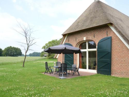 a building with a table and chairs and an umbrella at Quaint Farmhouse in Geesteren with Meadow View in Geesteren