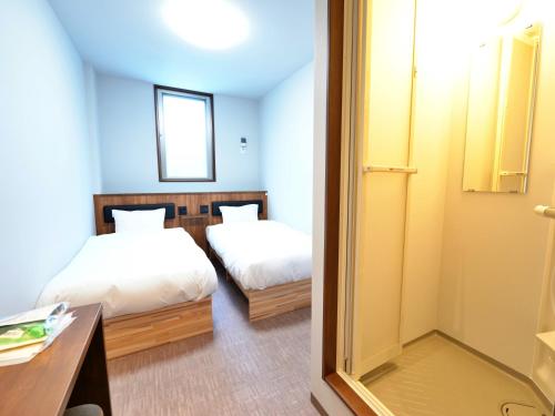 Habitación de hotel con 2 camas y espejo en HOTEL KANALOA, en Tokashiki