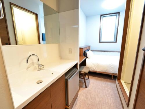 a bathroom with a sink and a bedroom with a bed at HOTEL KANALOA in Tokashiki