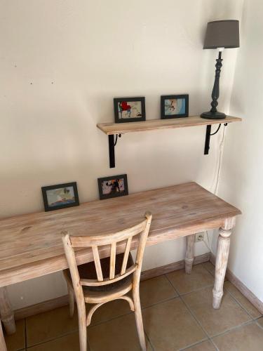 une table en bois avec une chaise et des photos encadrées dans l'établissement Pierres-Blanches, à Venasque