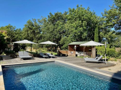 une piscine avec chaises longues et parasols dans l'établissement Pierres-Blanches, à Venasque