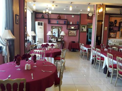 a dining room with tables and chairs with red tablecloths at Hotel Les Ambassadeurs in Oran