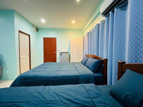 2 camas en un dormitorio con paredes azules en NUN GUEST HOUSE, en Ban Bo Han
