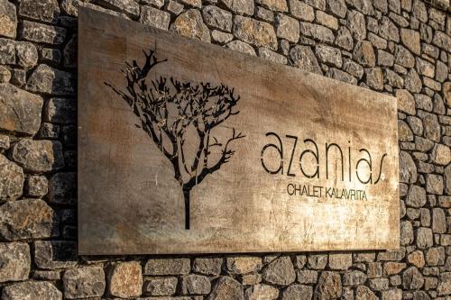 Un cartello su un muro di pietra con un albero sopra. di Chalet Azanias a Kalavrita