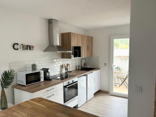 une cuisine avec des armoires blanches et un micro-ondes dans l'établissement Casanostra - T3 avec terrasse proche de Cassis, à Roquefort-la-Bédoule