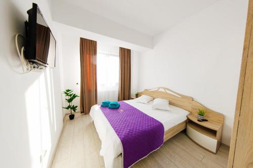 1 dormitorio con 1 cama con sábanas moradas y TV en 17 Zimbrului Residence at Lazar Towers Palas, en Iaşi