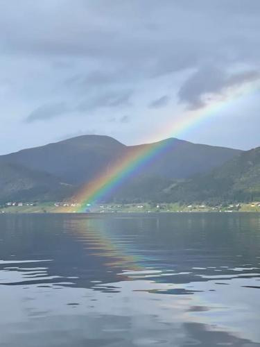 a rainbow over the water with mountains in the background at Krokenes in Sylte