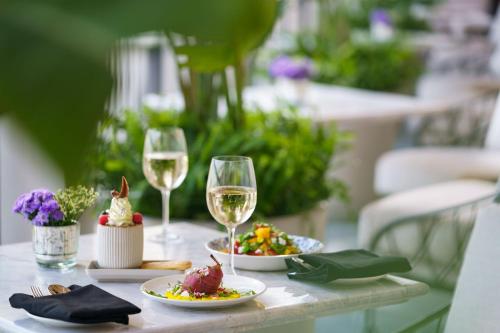 a table with two glasses of wine and plates of food at Taj Taal Kutir in Kolkata