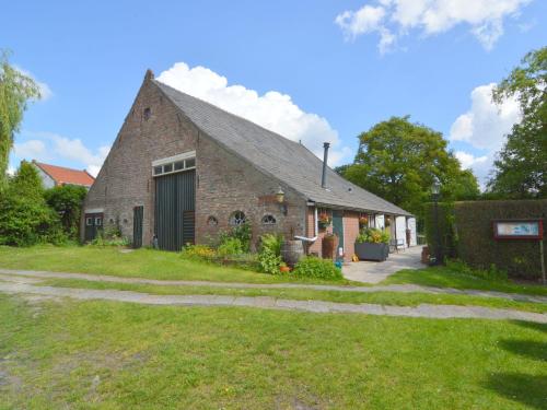 een oude bakstenen schuur met een grasveld bij Cozy Holiday Home in Bergen op Zoom with Garden in Bergen op Zoom