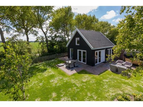 una pequeña casa negra diminuta en un patio en Family house with an ideal location private terrace garden and sauna, en Vrouwenpolder