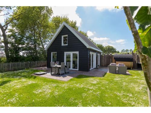 una pequeña casa negra con patio en Family house with an ideal location private terrace garden and sauna, en Vrouwenpolder