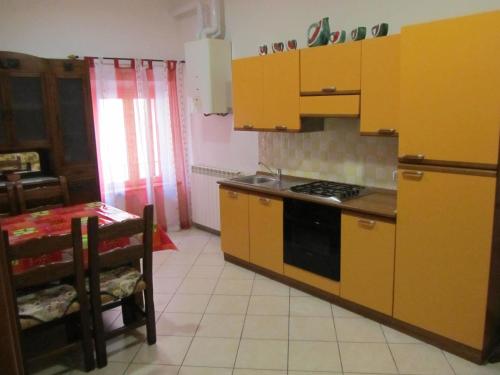 a kitchen with yellow cabinets and a table and a stove at Appartamento Leopardi in Castiglione della Pescaia