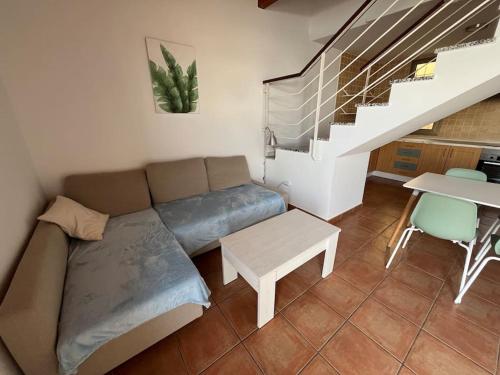 a living room with a couch and a table and stairs at CASA ALICIA - by 'Fuga A Fuerte' in Cotillo