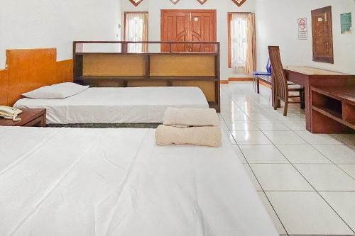 sypialnia z 2 łóżkami i biurkiem z ręcznikiem na podłodze w obiekcie Pandu Prima Guest House Syariah Mitra Reddoorz w mieście Bandung