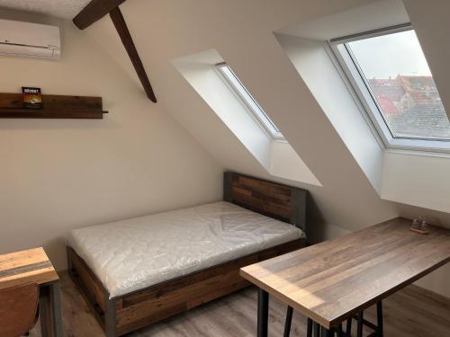 Habitación con cama, mesa y ventanas. en Zlonice - Ubytování 1kk, en Slaný