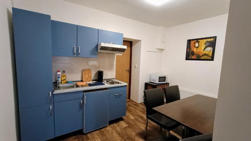a kitchen with blue cabinets and a dining table at Apartments Gato Karlovy Vary Dalovice in Karlovy Vary