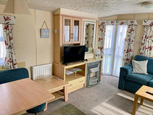 a living room with a tv and a couch and a table at Caravan hire Winthorpe Skegness in Skegness