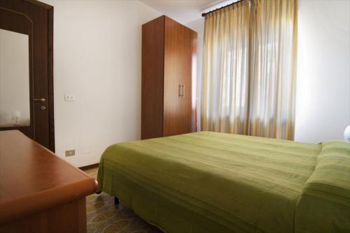 a bedroom with a green bed and a window at Appartamenti SA in Follonica