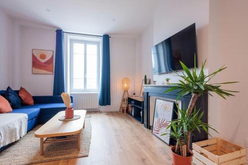 uma sala de estar com um sofá azul e uma televisão em Appart Jean Jaurès - 2 min gare - centre ville em Bourg-en-Bresse