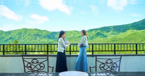two women standing on a balcony with mountains in the background at Hakone Sengokuhara Prince Hotel in Hakone