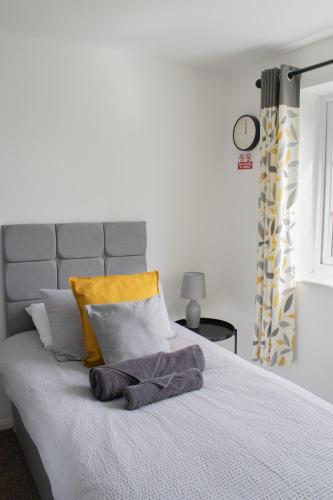a bed with yellow and white pillows and a clock at The Live and Let Live in Downham Market