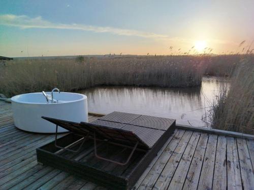 una bañera sentada en una terraza junto a un cuerpo de agua en Pfahlbau Rust/Neusiedlersee Sunset II, en Rust