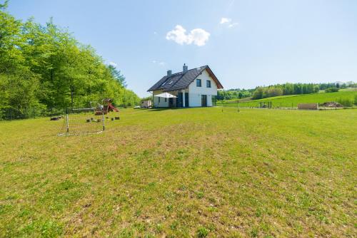 um grande campo com uma casa ao fundo em Peaceful house with sauna em Nowe Czaple