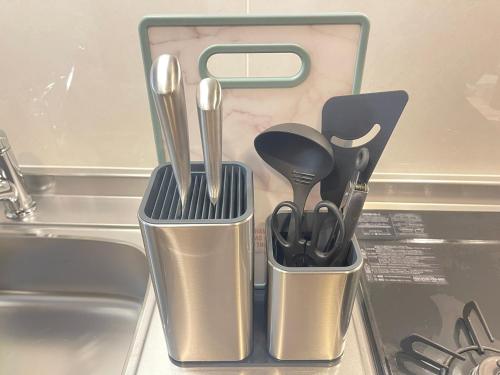 a container with utensils sitting on top of a sink at COCOSTAY銀山町リバーサイド,COCOSTAY Kanayamacho riverside, Great location river view-5 min walk from the nearest station in Hiroshima