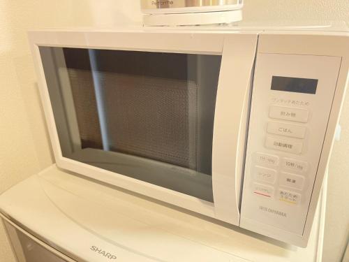 a white microwave oven sitting on top of a cabinet at COCOSTAY銀山町リバーサイド,COCOSTAY Kanayamacho riverside, Great location river view-5 min walk from the nearest station in Hiroshima
