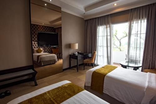 Habitación de hotel con 2 camas y un espejo grande. en The Mirah Bogor en Bogor