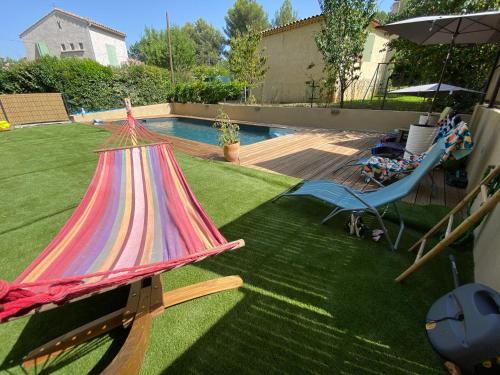 - un hamac coloré dans une cour à côté d'une piscine dans l'établissement Superbe villa avec piscine, jardin et terrasse aux portes d'Aix en Provence, à Aix-en-Provence