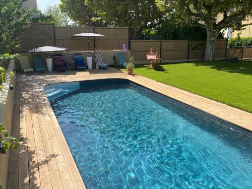 - une piscine dans une cour avec des chaises et des parasols dans l'établissement Superbe villa avec piscine, jardin et terrasse aux portes d'Aix en Provence, à Aix-en-Provence