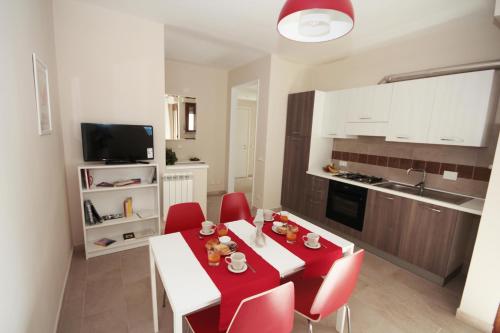 比薩的住宿－波奇帕西旅館，厨房配有红色和白色的桌子和红色的椅子