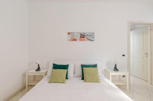 a white bed with green pillows in a room at Casa Regina 2, nel centro storico di Alba! in Alba