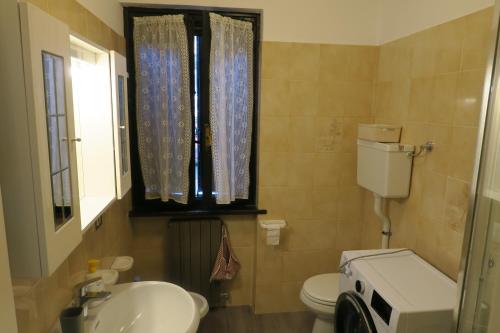 a bathroom with a toilet and a sink and a window at Appartamento Aila in Molina di Ledro
