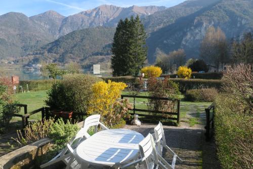 a table and chairs in a garden with mountains in the background at Appartamento Aila in Molina di Ledro