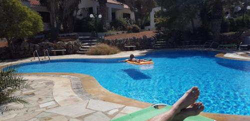 a person laying on a raft in a swimming pool at Kazamia Apartments with Sharing Pool in Agia Fotia