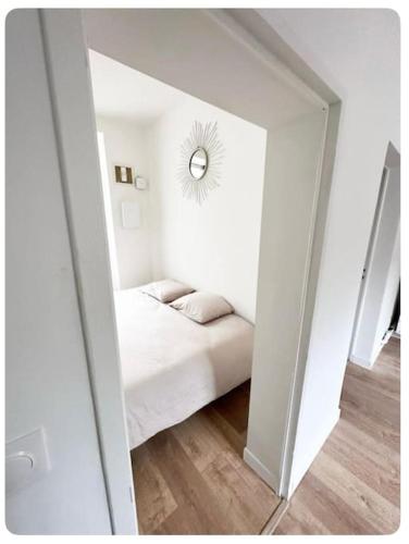 une chambre blanche avec un lit et un miroir dans l'établissement L'Ambre, à Angers