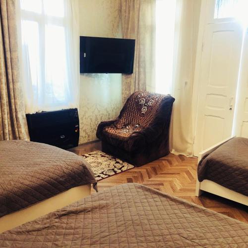 a bedroom with a chair and a bed and a television at Family House Shorety in Surami