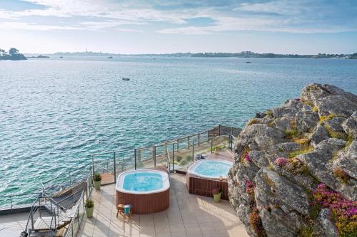 two hot tubs on a deck next to the water at Résidences Valdys Thalasso & Spa de Rockroum in Roscoff