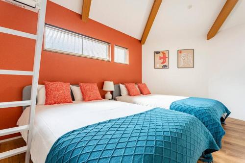 two bunk beds in a room with orange walls at Fully furnished house for families with infants. in Osaka