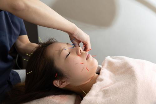 a woman is getting her face examined by a womanractor at 城崎温泉 HOSTEL Waraku in Kinosaki