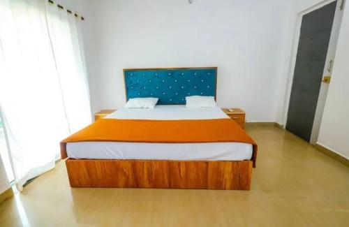 a bedroom with a bed with an orange and white blanket at Hotel Vaibhav Hill Park in Mapusa