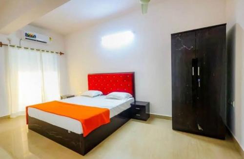 a bedroom with a large bed with an orange blanket at Hotel Vaibhav Hill Park in Mapusa