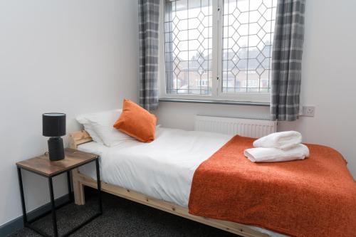 a bedroom with a bed with an orange blanket and a window at Spacious, Contractors, Long Term Discounts in Birmingham