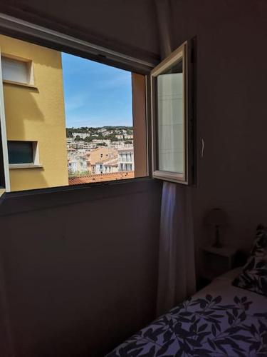 une chambre avec une fenêtre avec vue sur une ville dans l'établissement Appartement bord de plage, à Cassis