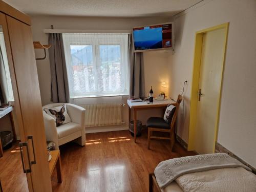 a bedroom with a desk and a bed and a window at Hotel Paradis-Leukerbad-Therme in Leukerbad