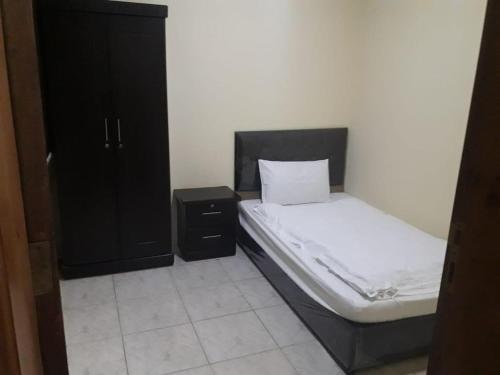 a bedroom with a bed and a black cabinet at دانية للأجنحة الفندقية in Al Jubayl