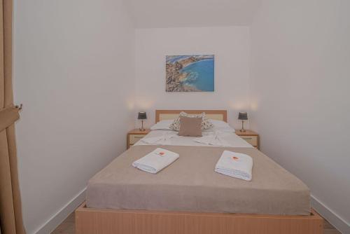 a bedroom with a bed with two towels on it at Guest House S-Lux in Petrovac na Moru